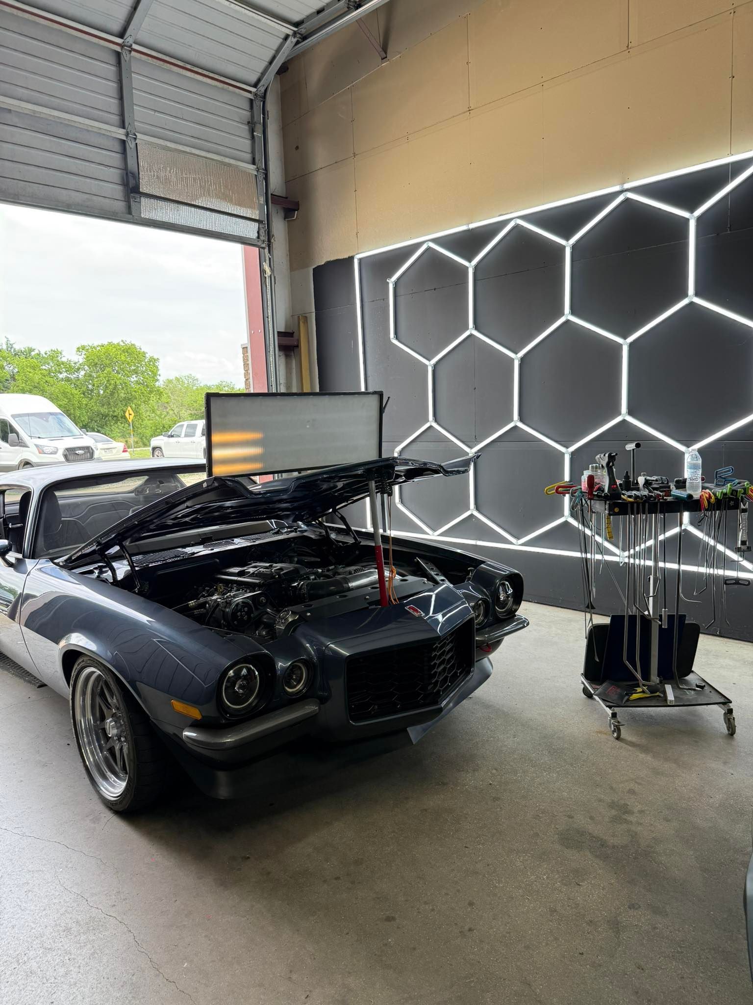 Classic gray car in a repair shop with the hood open.