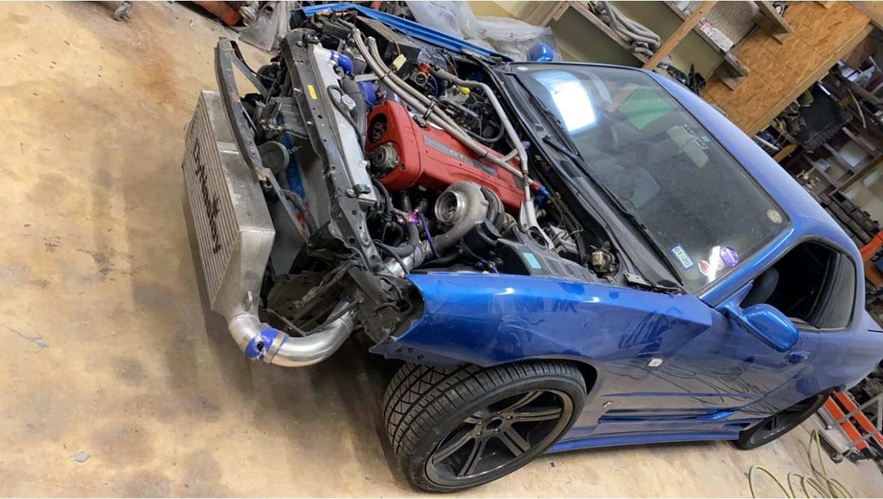 Blue sports car with the hood open, revealing a modified engine and mechanical components.