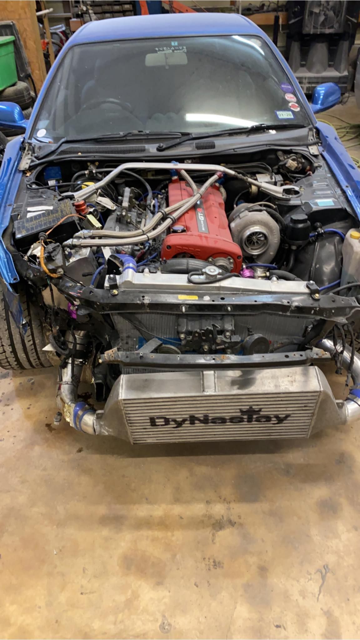 Blue sports car with front end dismantled, revealing engine components and intercooler.