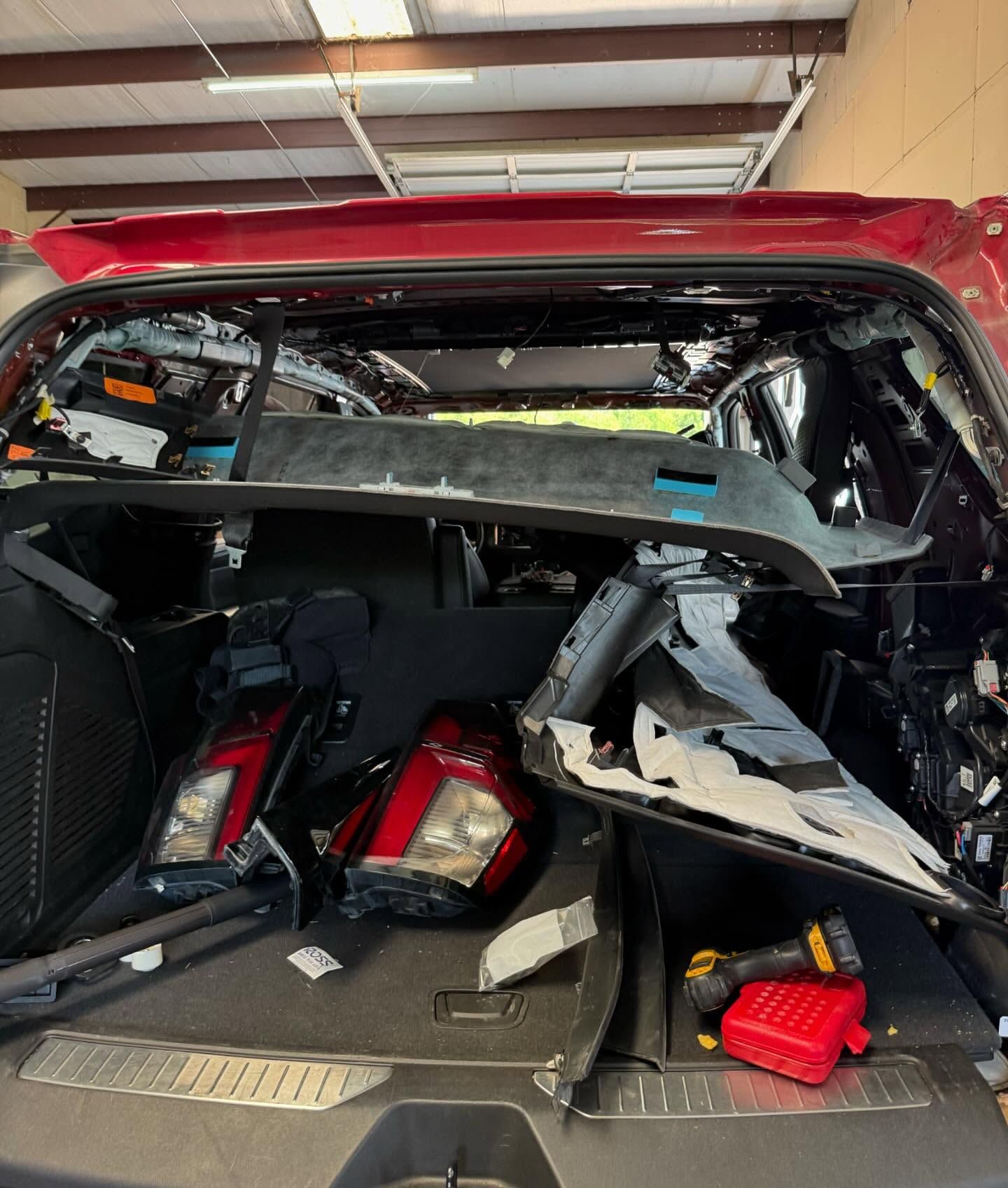 Red car interior disassembled, with taillights, tools visible.