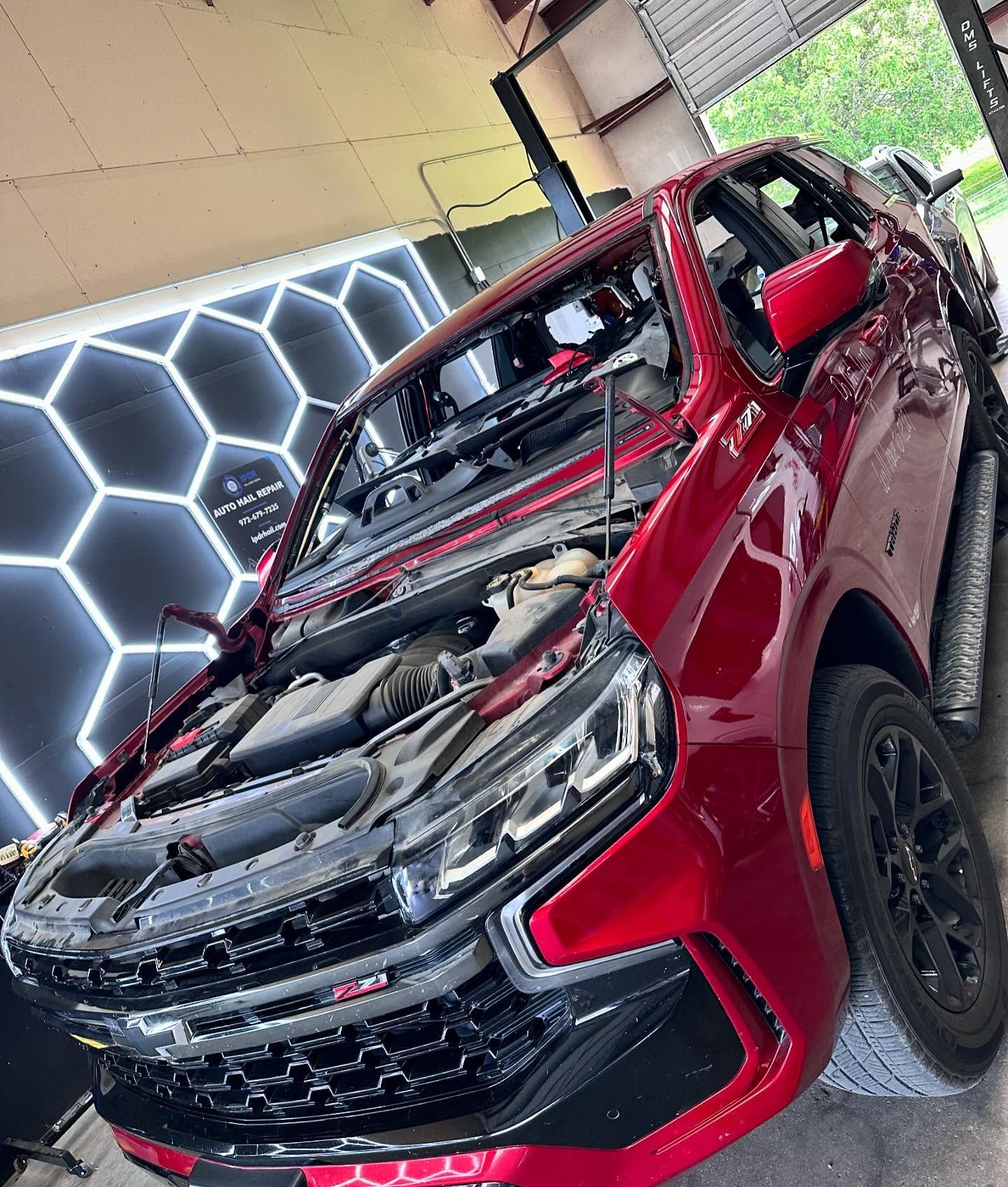 Red SUV in a garage with the hood open, undergoing maintenance.