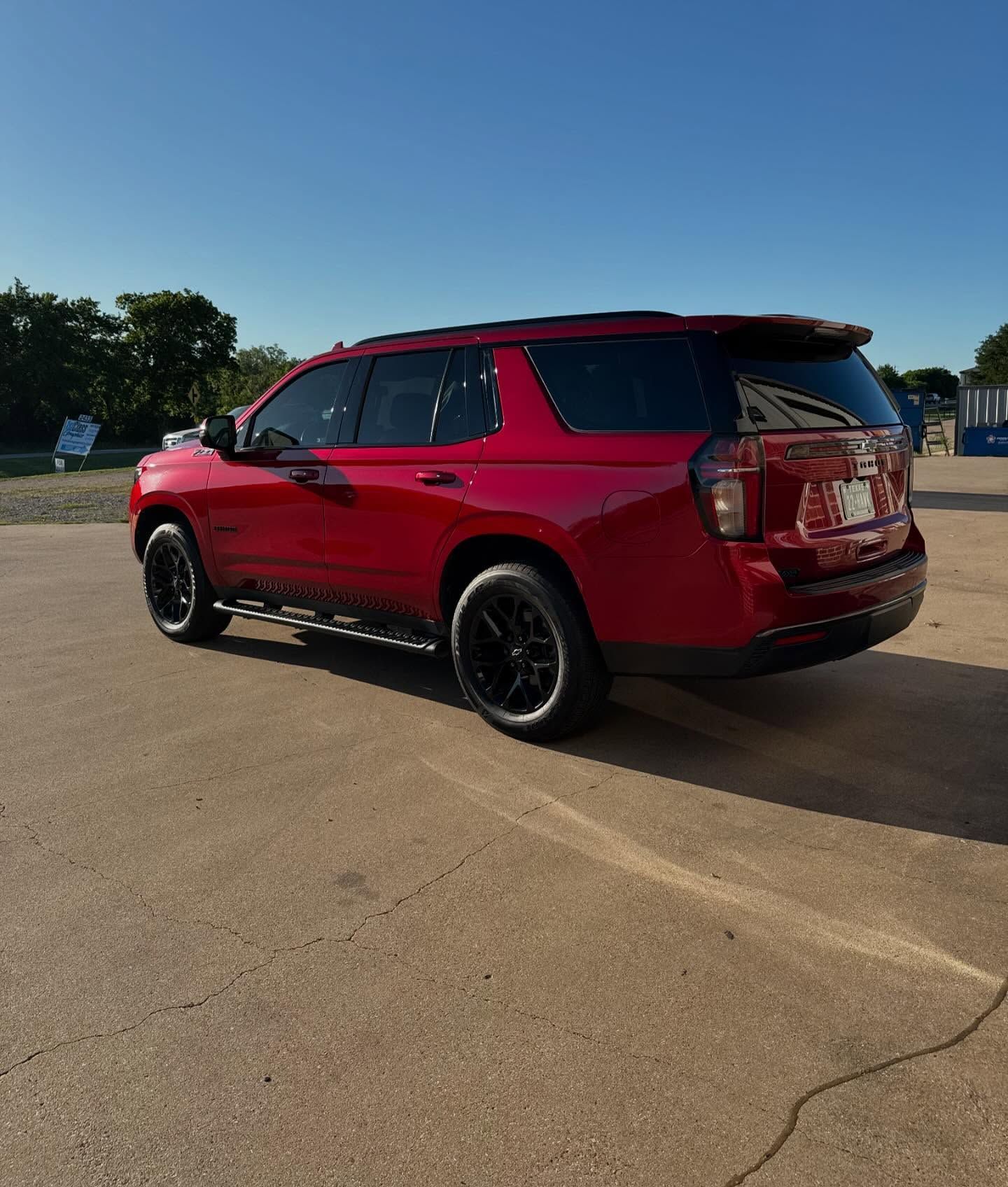 Red Chevy Tahoe SUV parked on pavement on a sunny day.