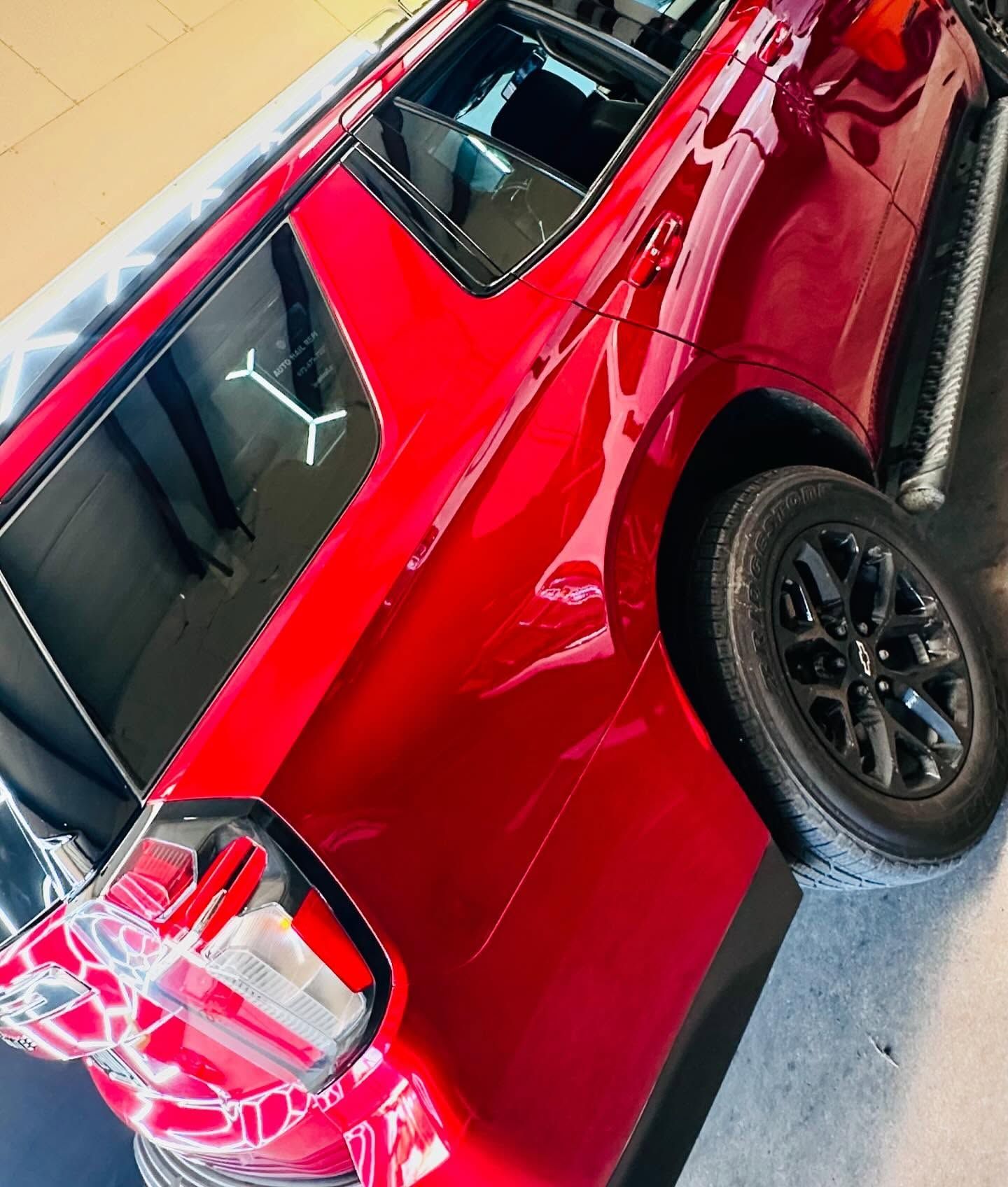 Red SUV with black wheels, tinted windows, and chrome side steps parked indoors.