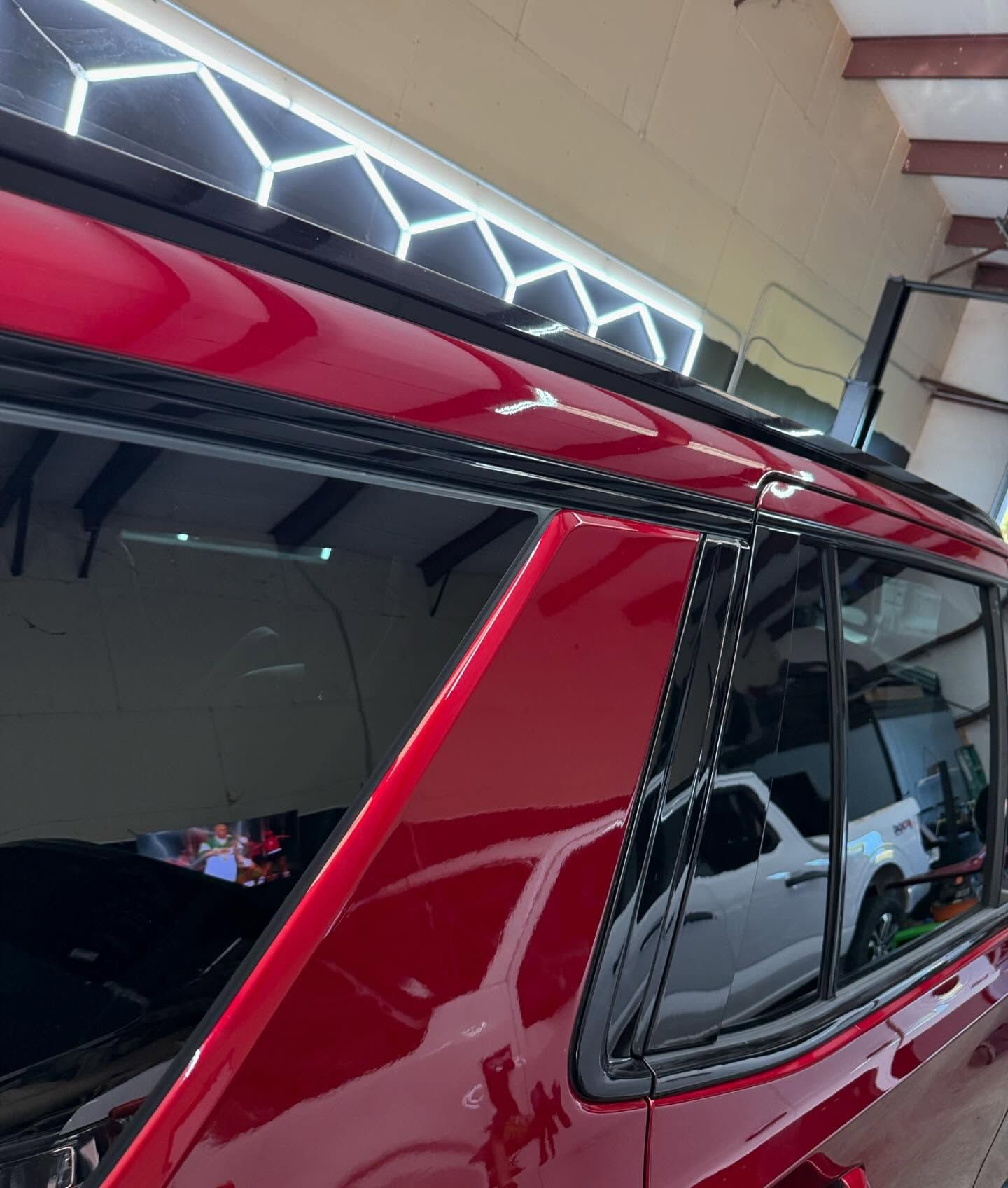 Red SUV with tinted windows, parked in a garage with black trim.