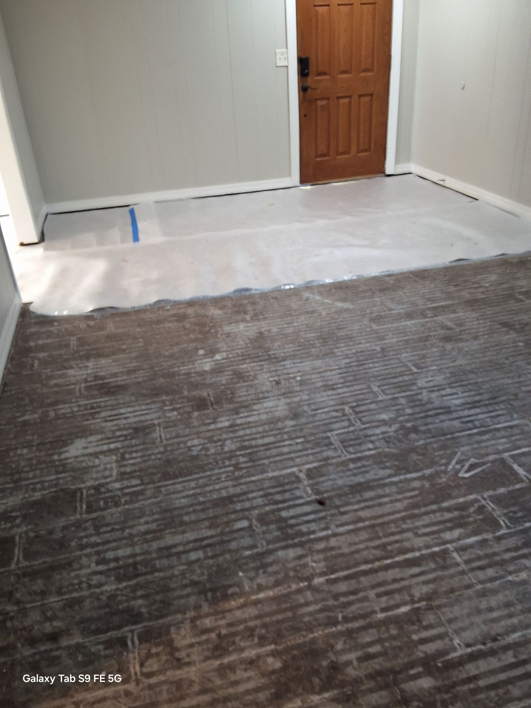 A room with a wooden door and a carpet on the floor.