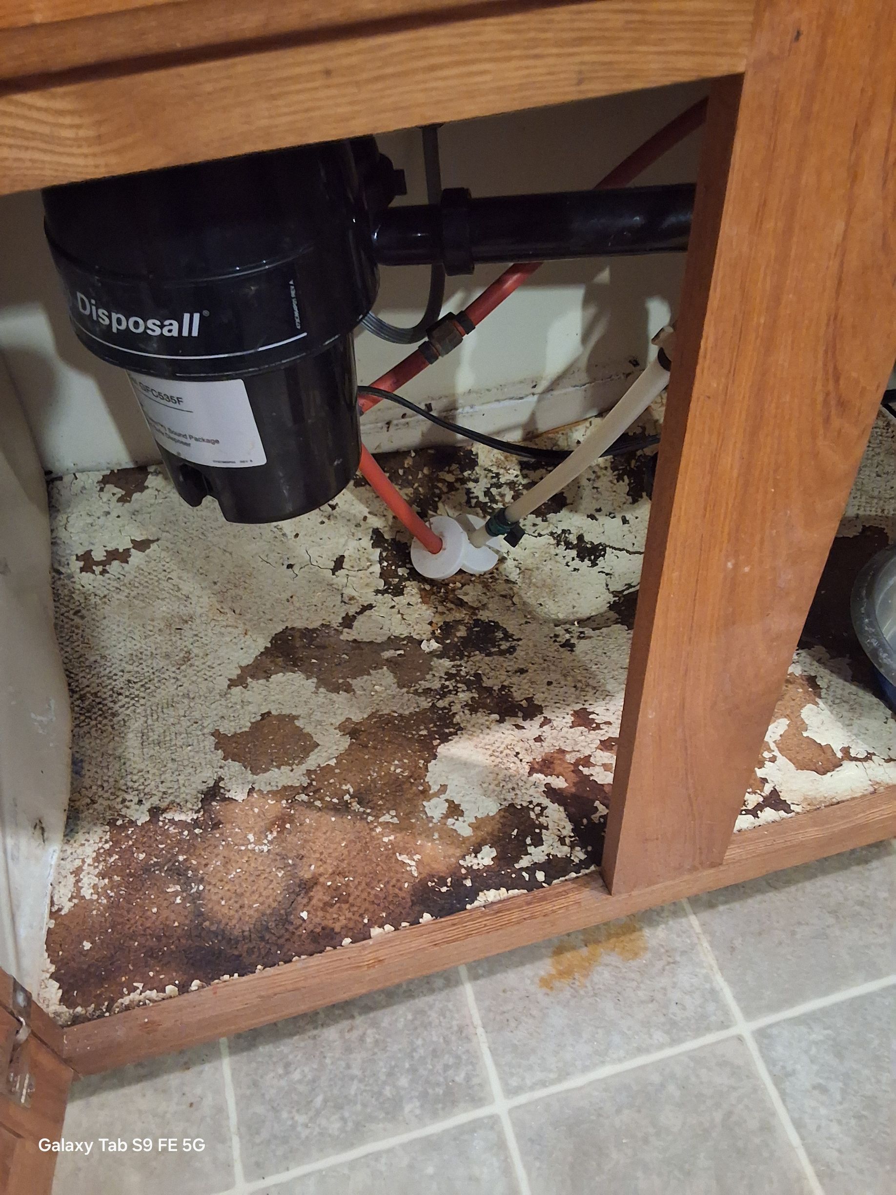 A garbage disposal is sitting under a kitchen sink.