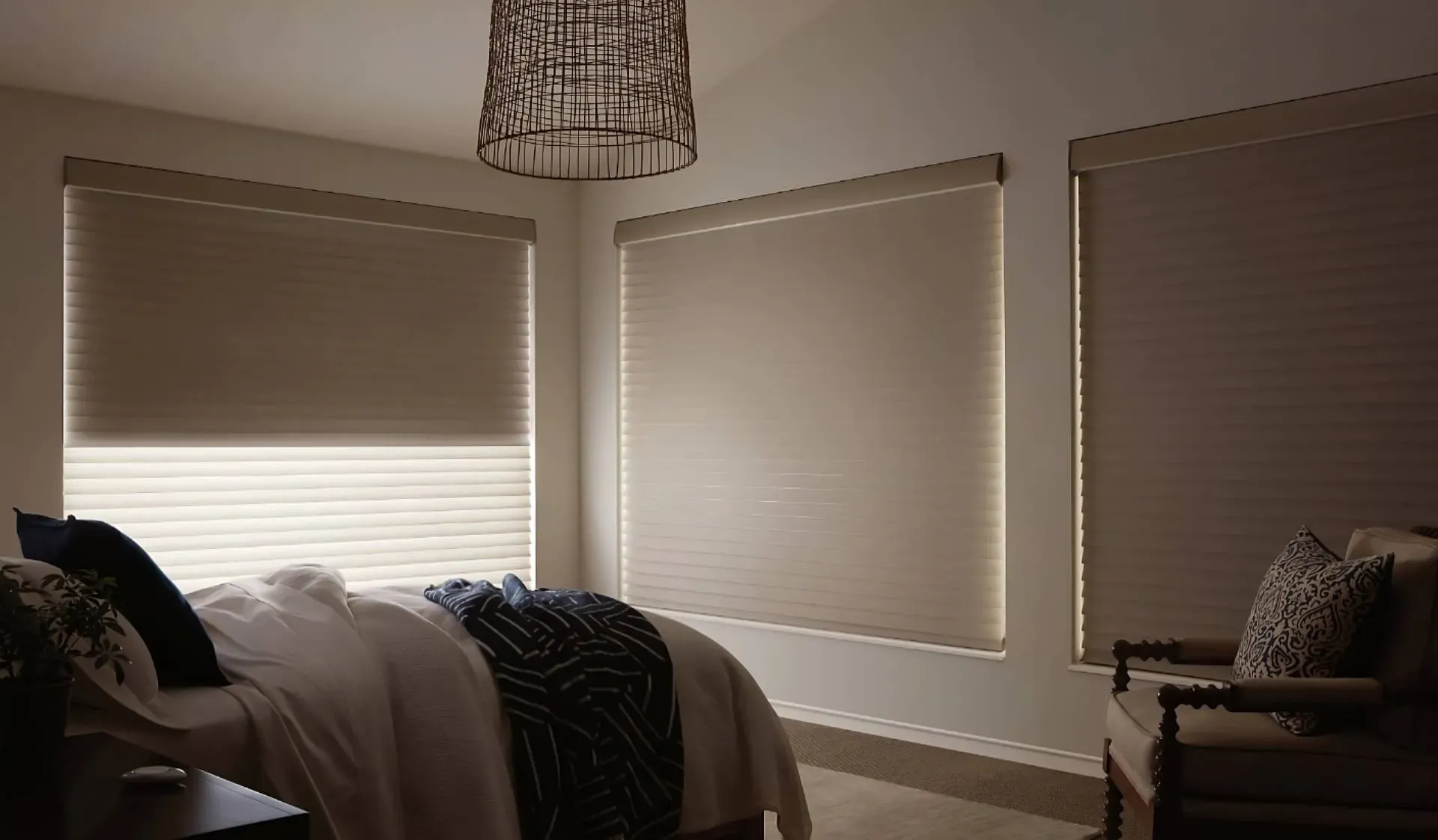 Automatic shades on three bedroom windows with the PowerView® Pebble® Remote on the nightstand