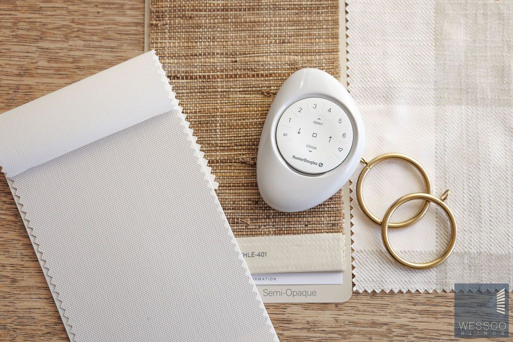 Samples of fabric, a remote control, and curtain rings on wood.