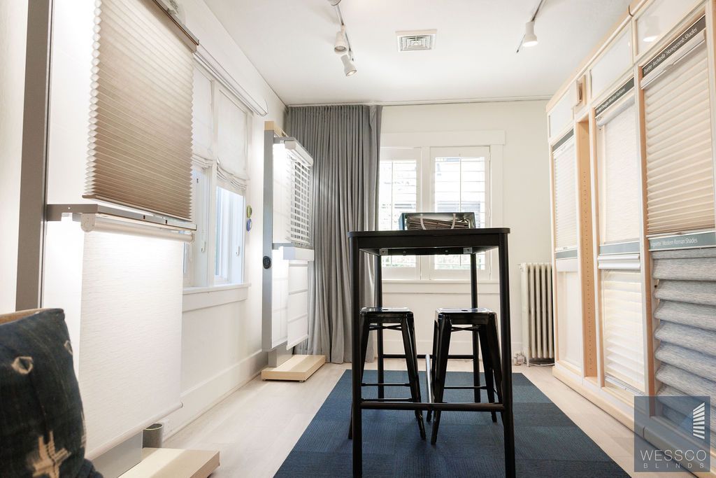 Interior showroom with window coverings, table and stools, and blue rug.