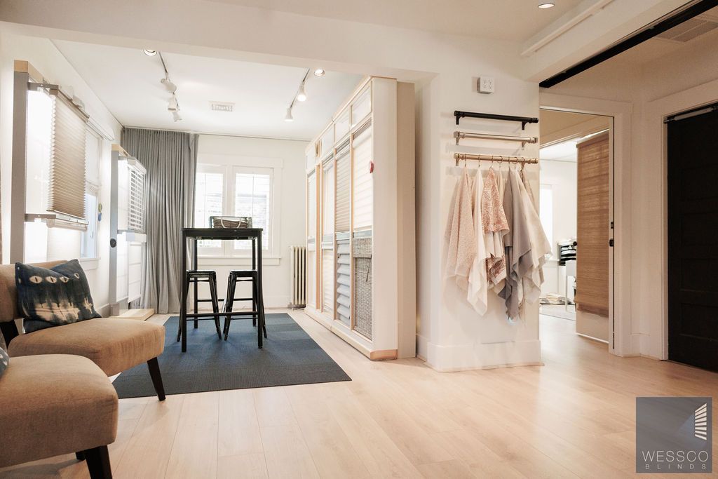 Interior of a modern dressing room with light wood floors, a closet, seating, and clothing racks.