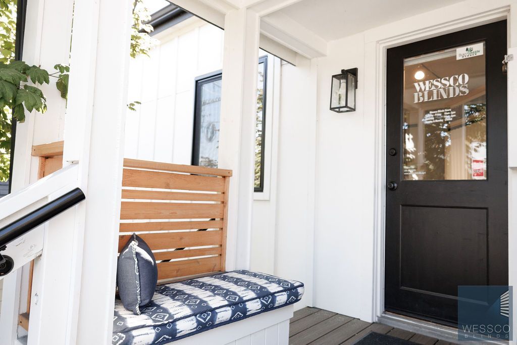 Exterior of a white building with a black door, bench, and window.