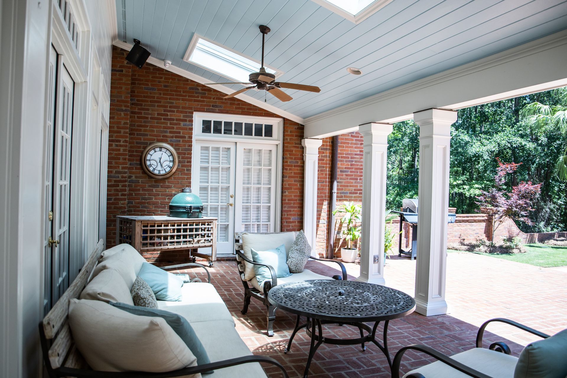 A well-decorated outdoor patio with blue accents and sunshades on the patio's French doors