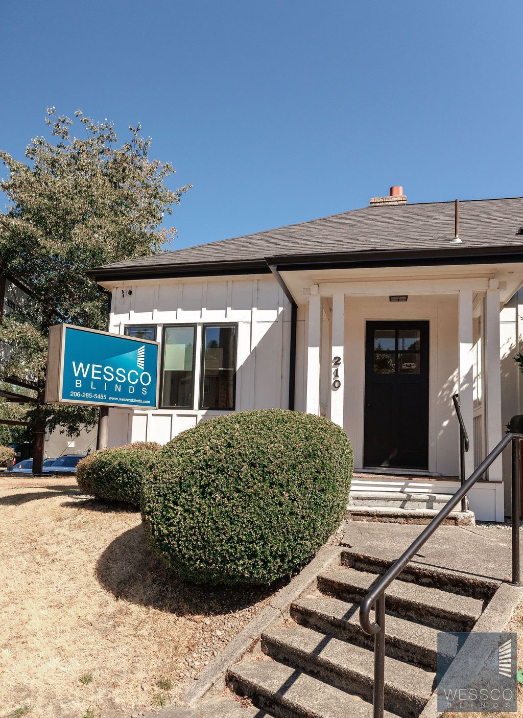 A white building with a black door, a sign reading 