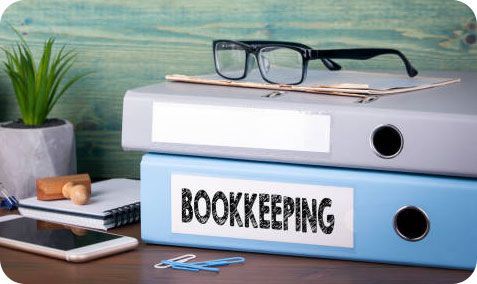 A stack of bookkeeping binders sitting on top of each other on a desk.