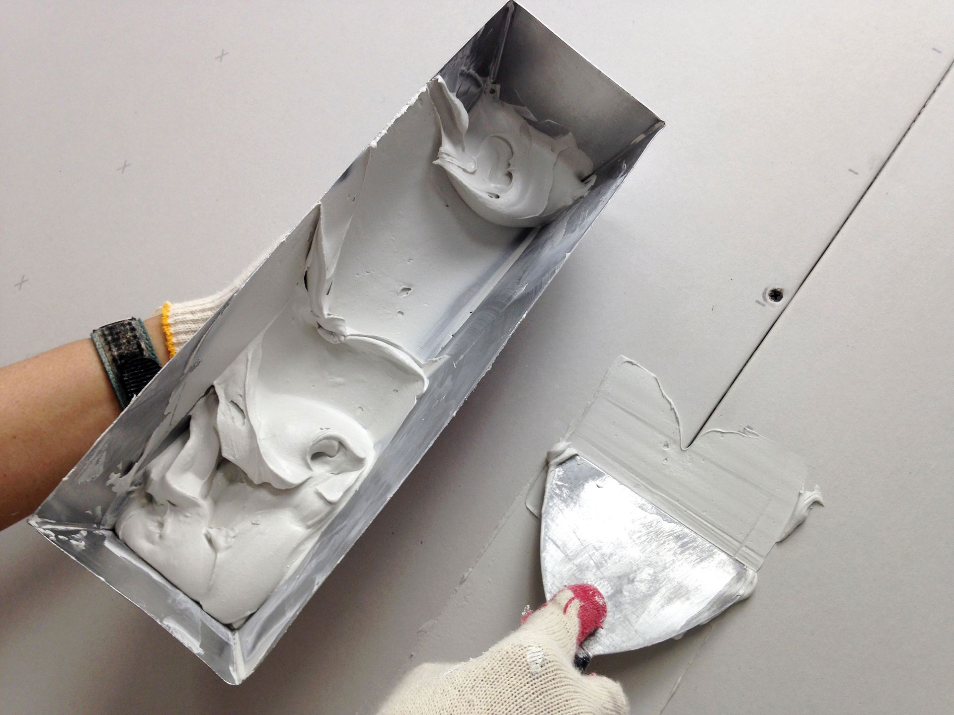 A person is applying plaster to a wall with a spatula.