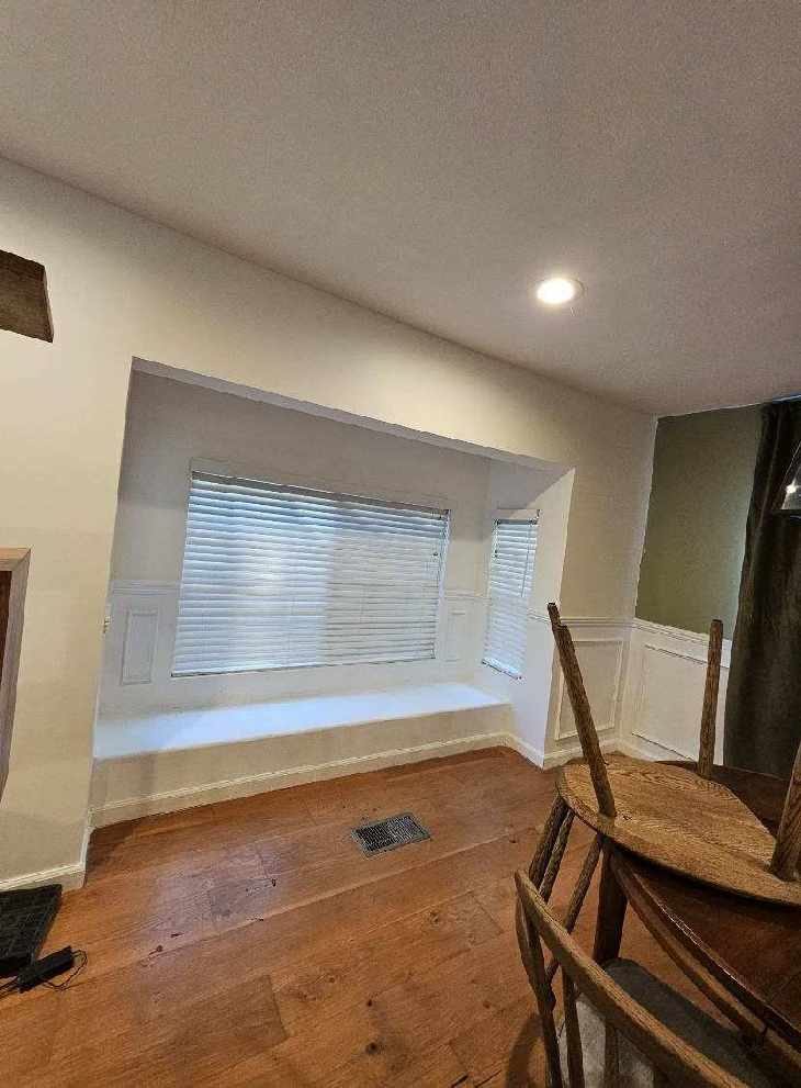 A dining room with a table and chairs and a window seat.
