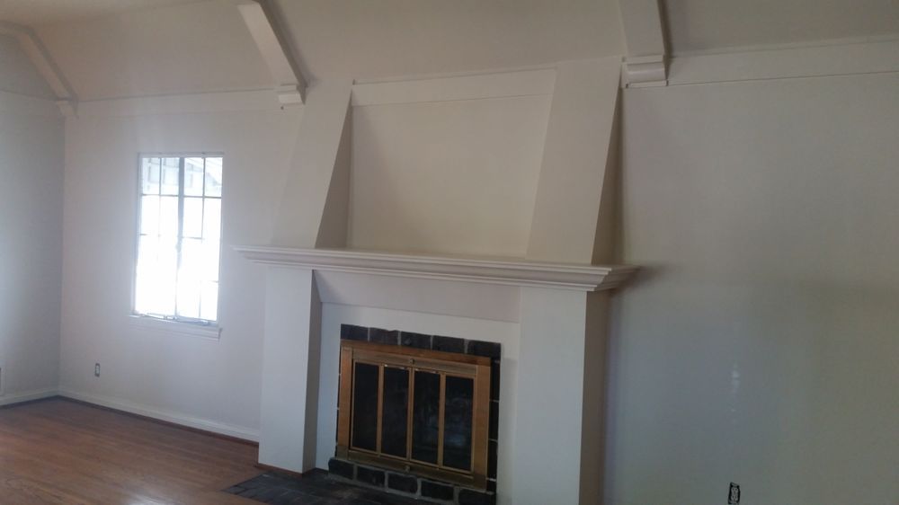 An empty living room with a fireplace and a window. An empty living room with a fireplace and a window.