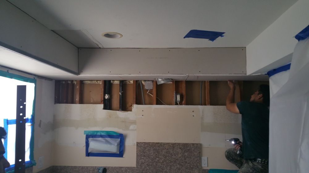 A man is working on the ceiling of a bathroom. A man is working on the ceiling of a bathroom.