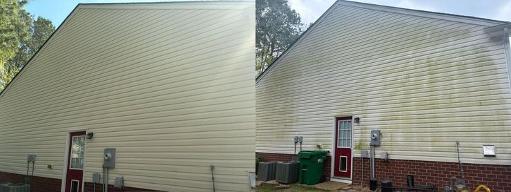 White-sided house exterior with a small window, brick foundation, and a satellite dish near a wooden fence.