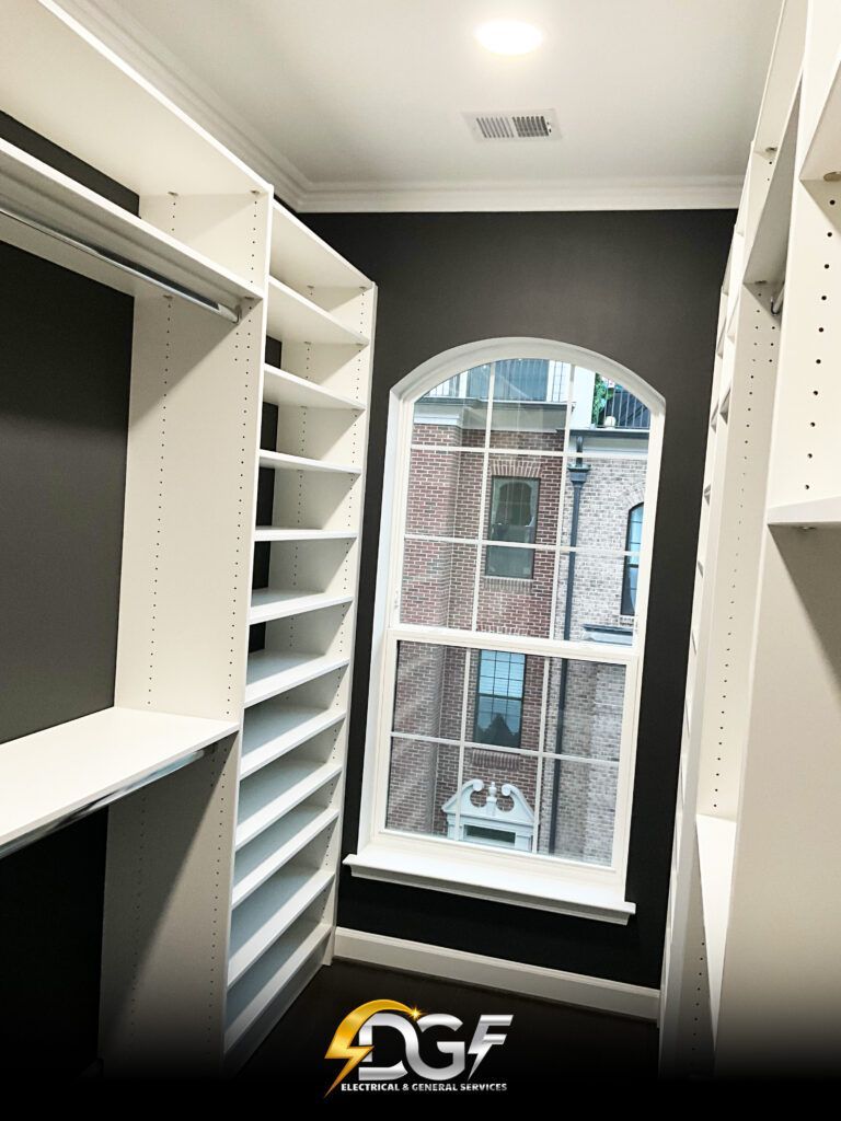 A walk in closet with white shelves and a window.