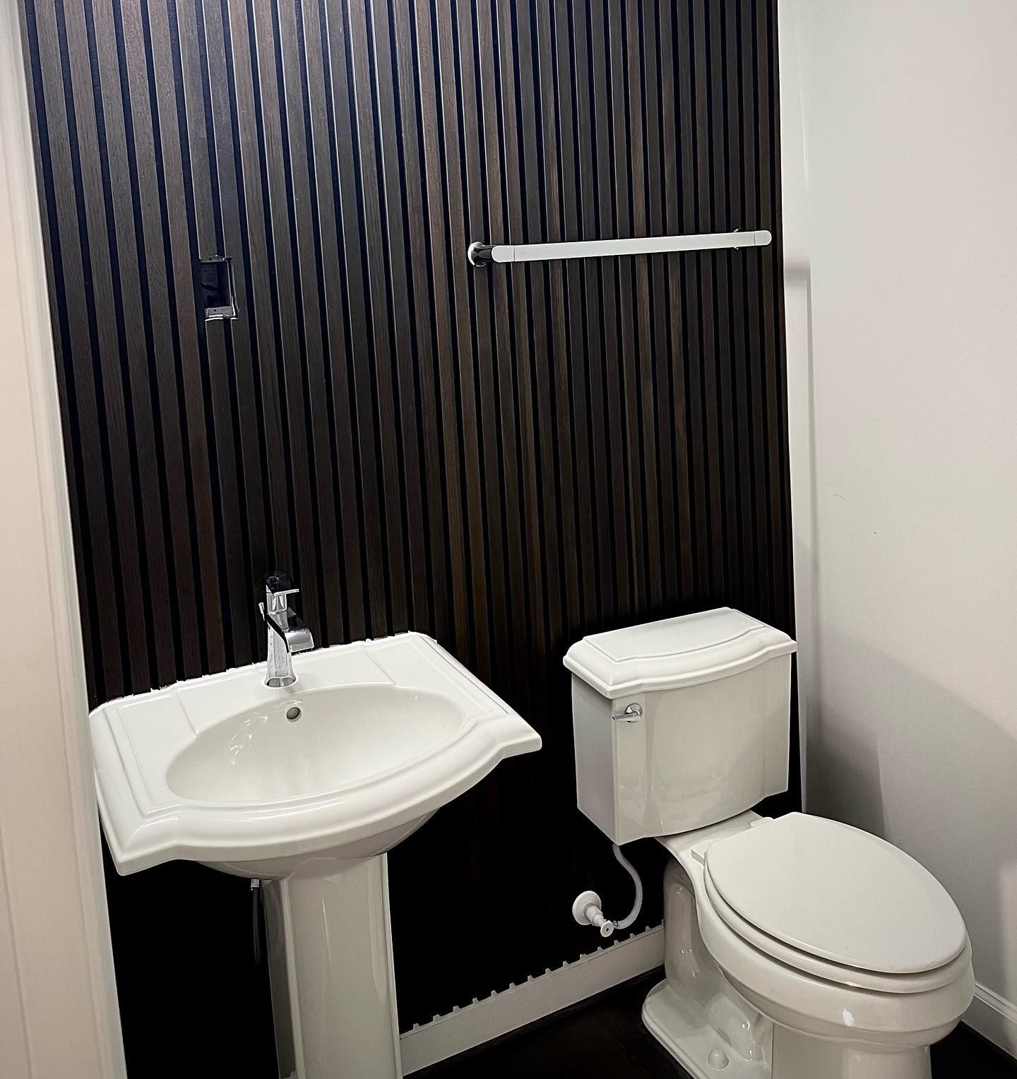 A bathroom with a toilet a sink and a towel rack