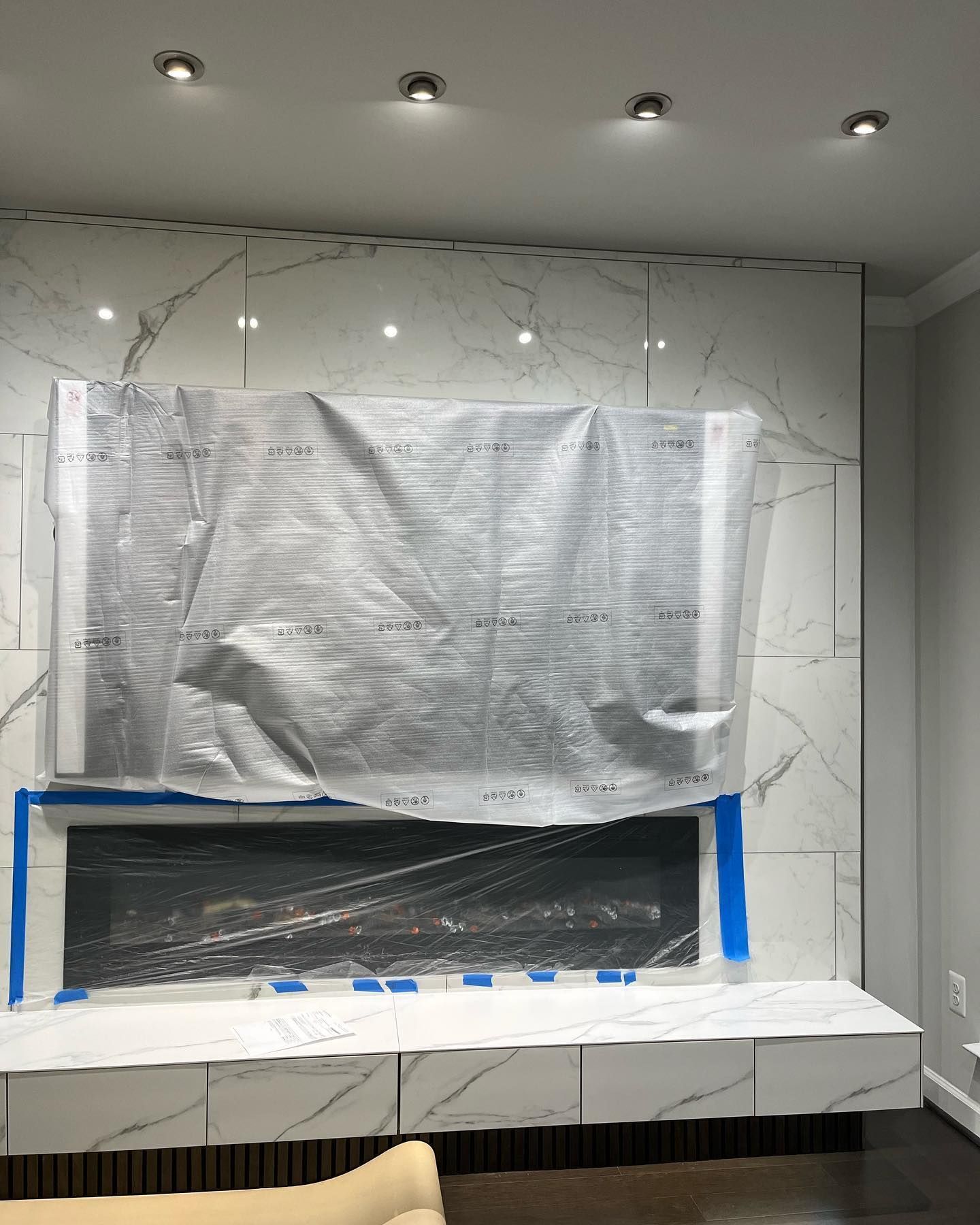 A living room with a fireplace covered in plastic wrap.