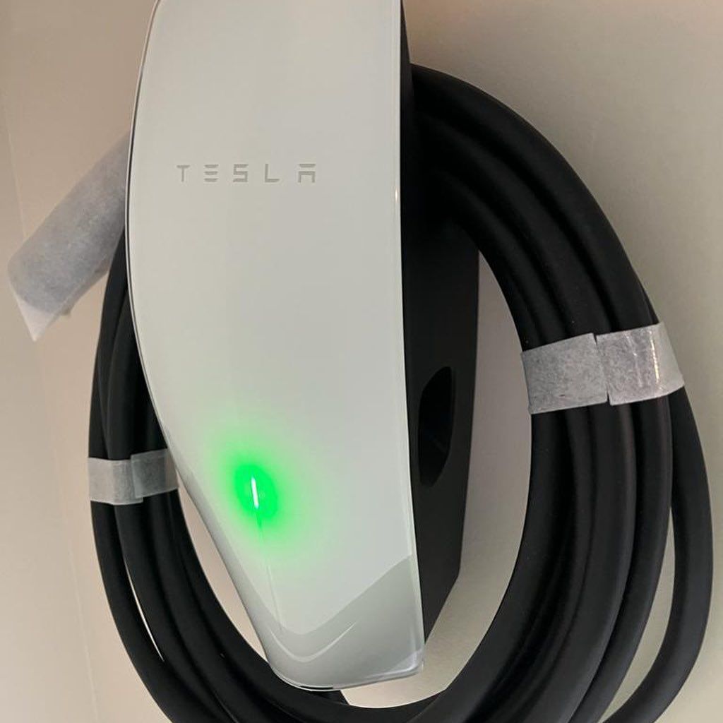 A tesla charger with a green light on it