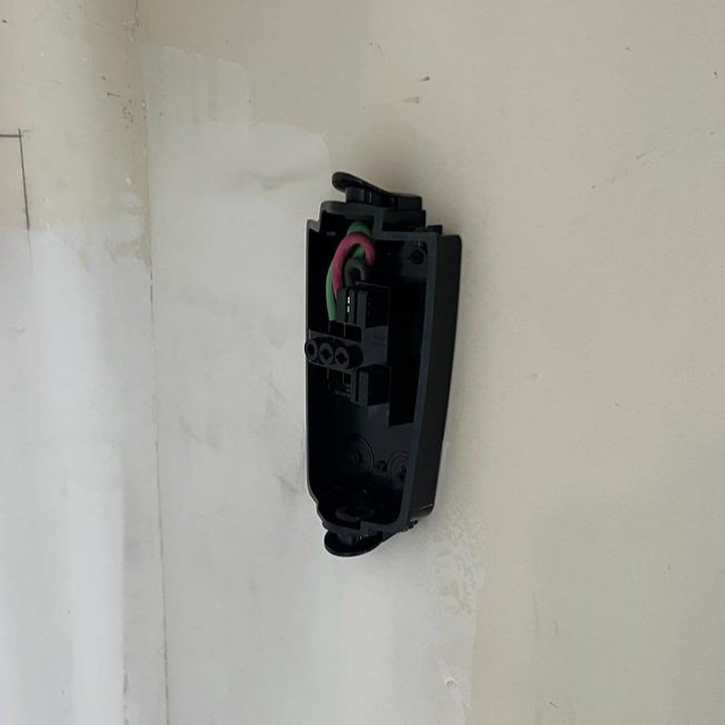 A black box is hanging on a white wall.