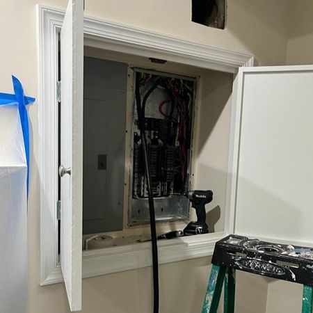 A ladder is sitting next to a electrical box in a wall.
