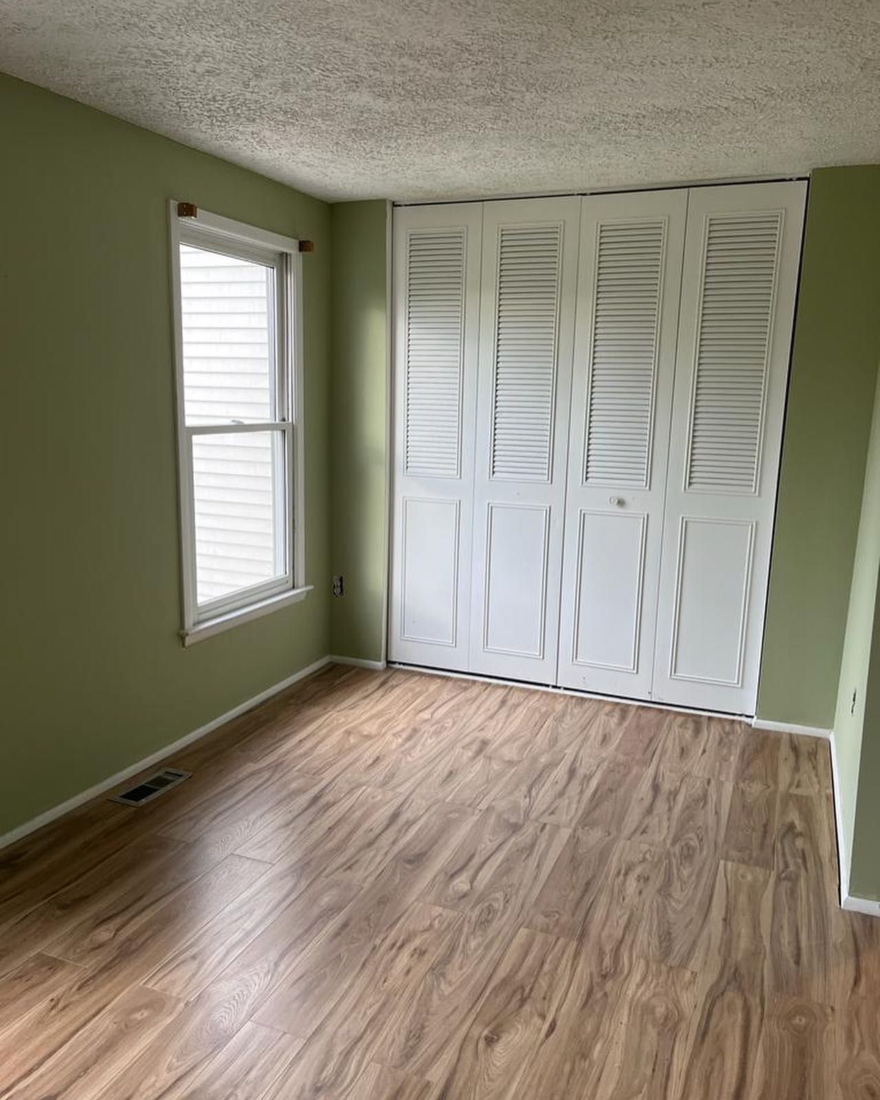 An empty room with hardwood floors , a window and a closet.