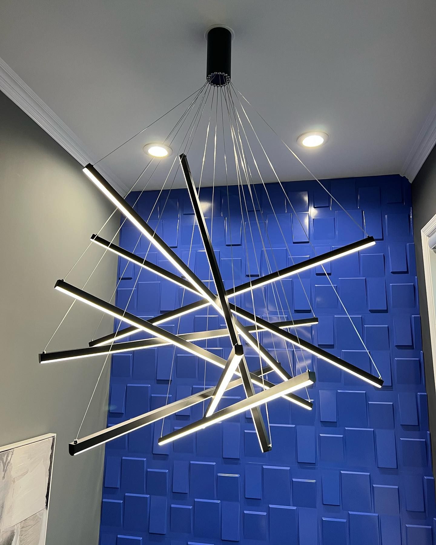 A chandelier is hanging from the ceiling in a room with a blue wall.