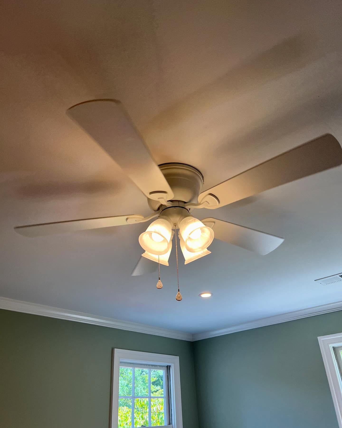 A bedroom with a ceiling fan and a window.