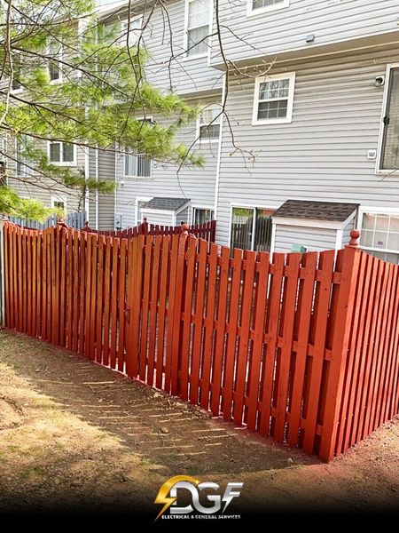 A red wooden fence is in front of a house.