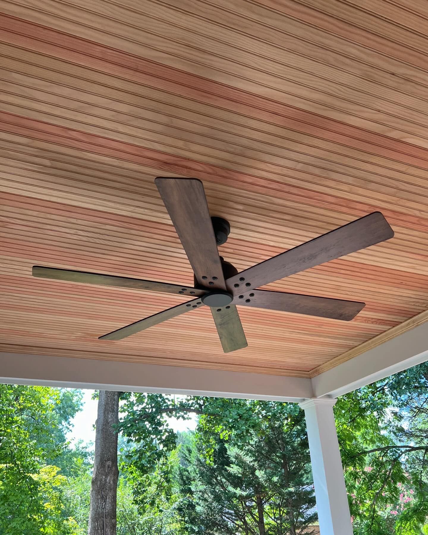 A ceiling fan is hanging from the ceiling of a porch.