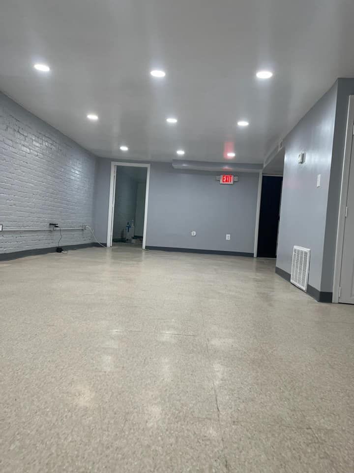 A large empty room with a brick wall and a white floor.
