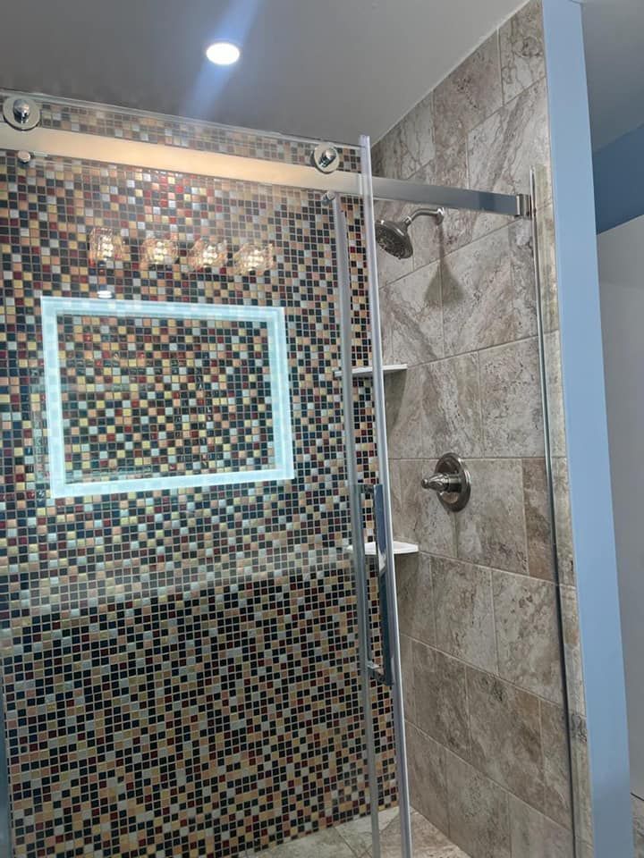 A bathroom with a walk in shower and a mosaic wall.