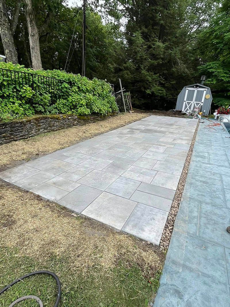 A concrete patio is being built in a backyard.