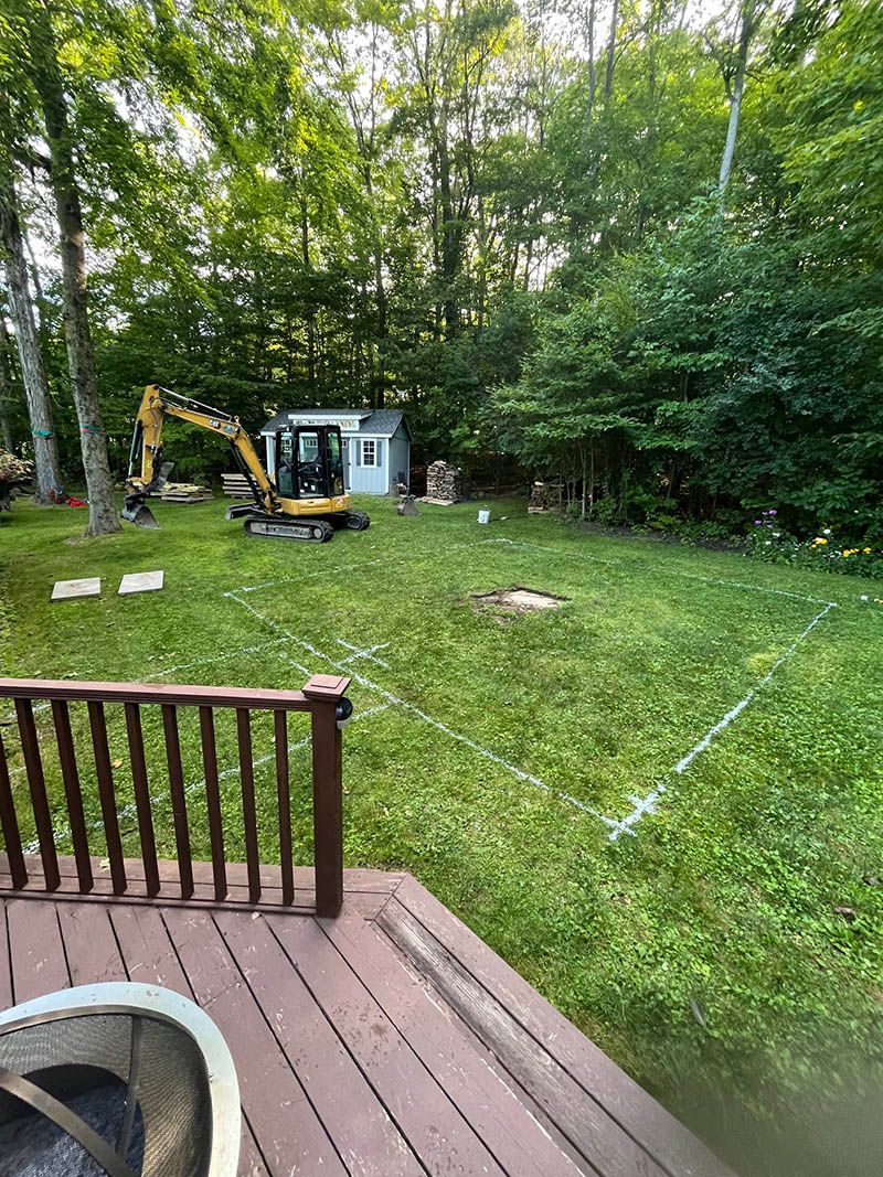 A backyard with a deck and a bulldozer in the grass.