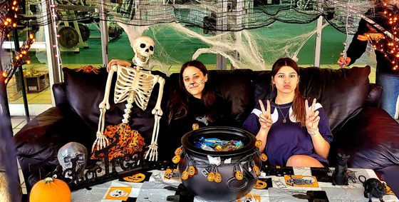 Two young girls are sitting at a table in the woods.