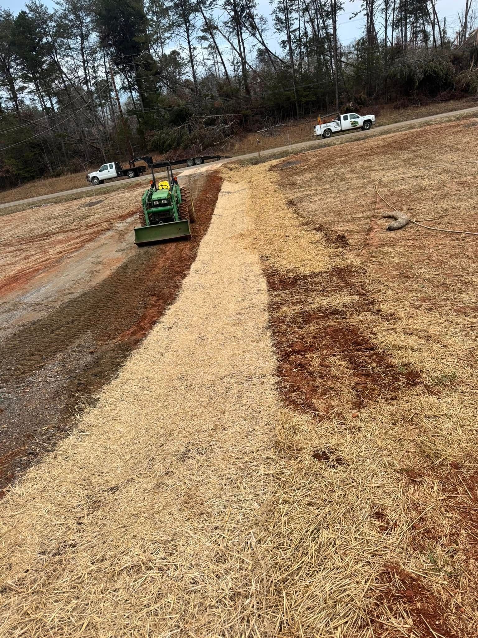 A tractor is driving down a dirt road.