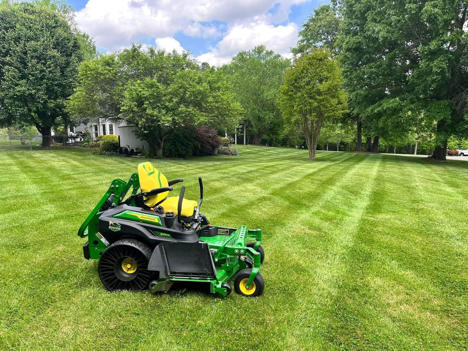 A green lawn mower is sitting on top of a lush green lawn.