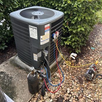 AC unit being serviced outdoors with gauges, hoses, and a vacuum pump.