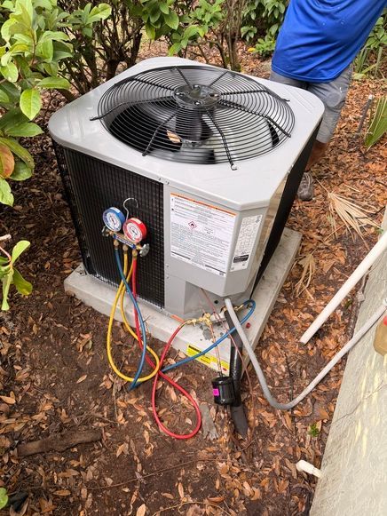 Air conditioning unit being serviced outdoors, with gauges attached.