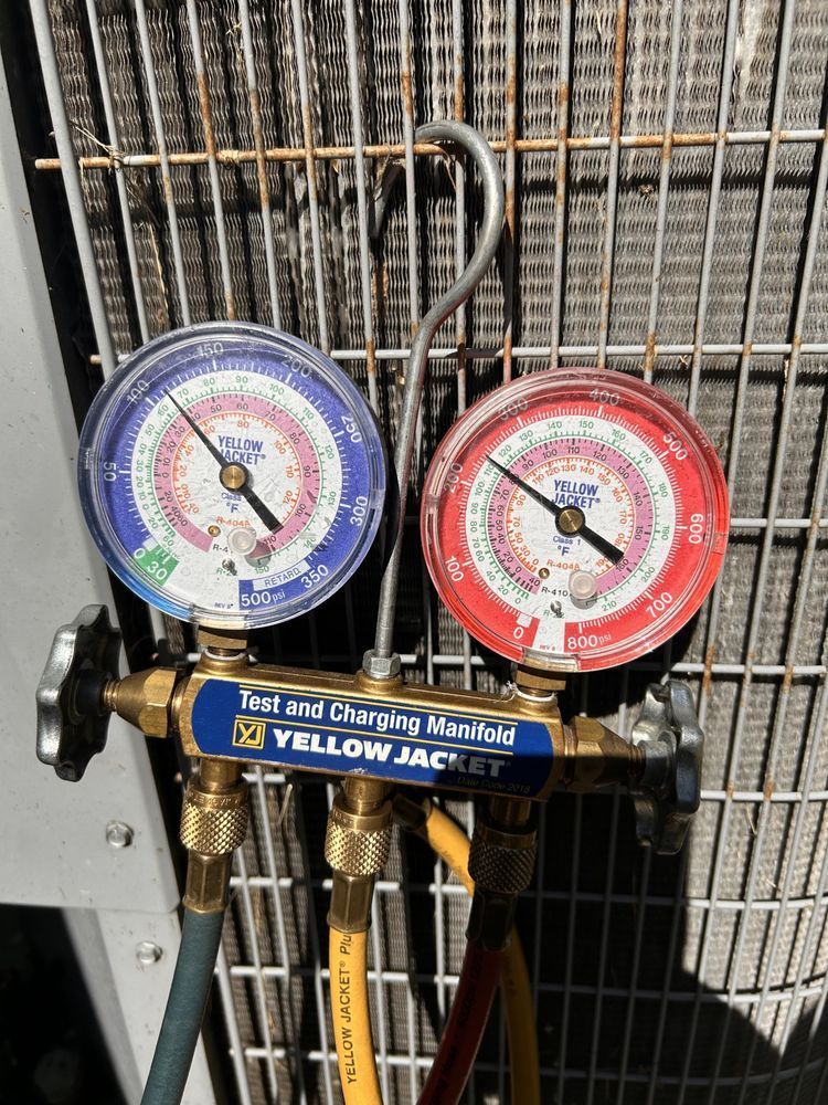 Yellow Jacket manifold gauges connected to HVAC unit. Blue and red gauges, hoses, and valve.