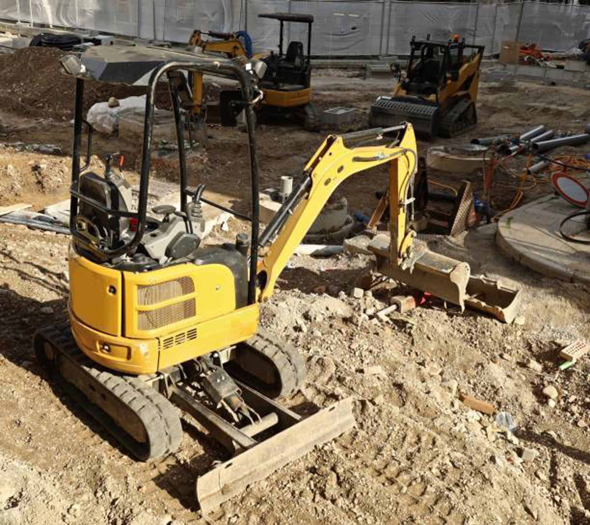 Person opening a manhole cover with a tool in a grassy area.