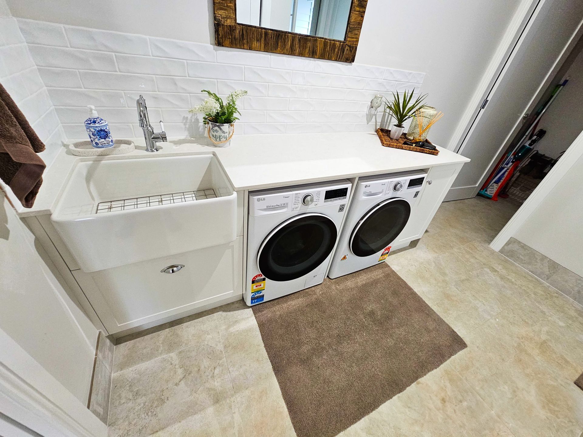 A laundry room with a sink , washer and dryer , and a mirror.