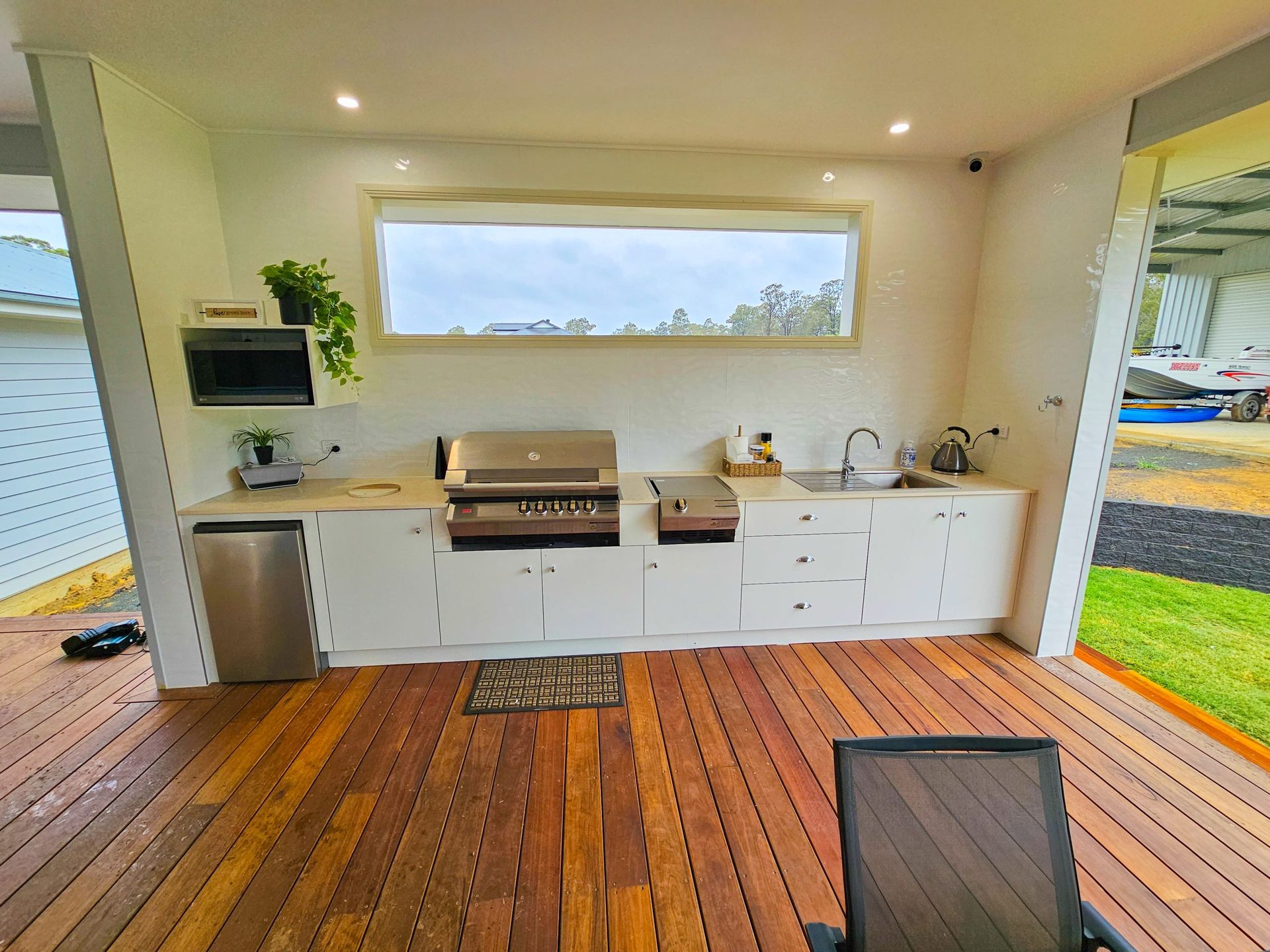 A kitchen with a grill and a sink on a wooden deck.