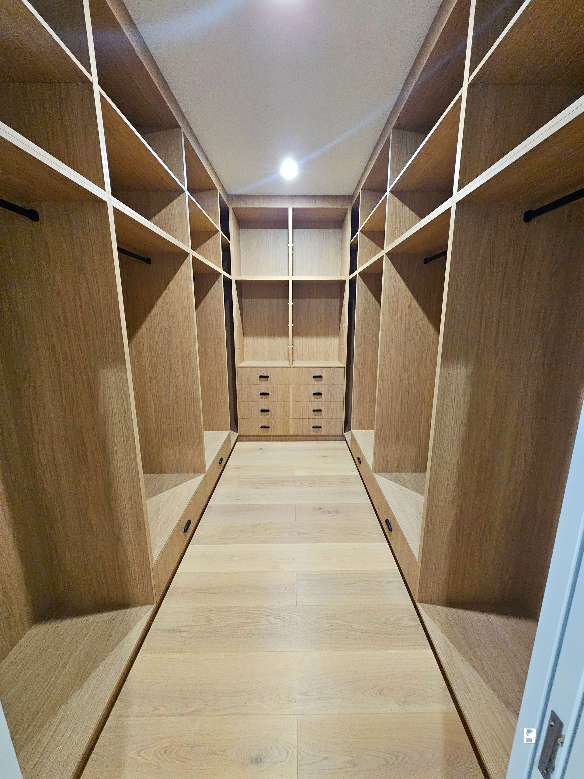 A large walk in closet with lots of clothes and shoes