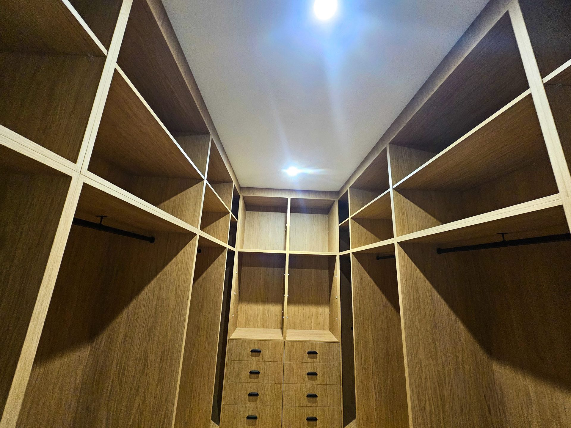 A walk in closet with lots of shelves and drawers