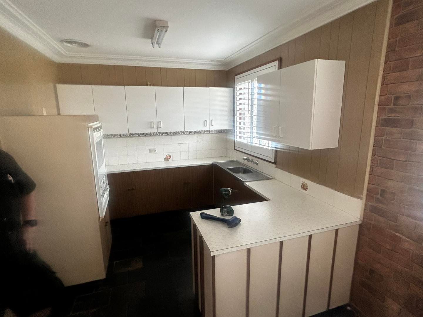 A kitchen with white cabinets and a brick wall